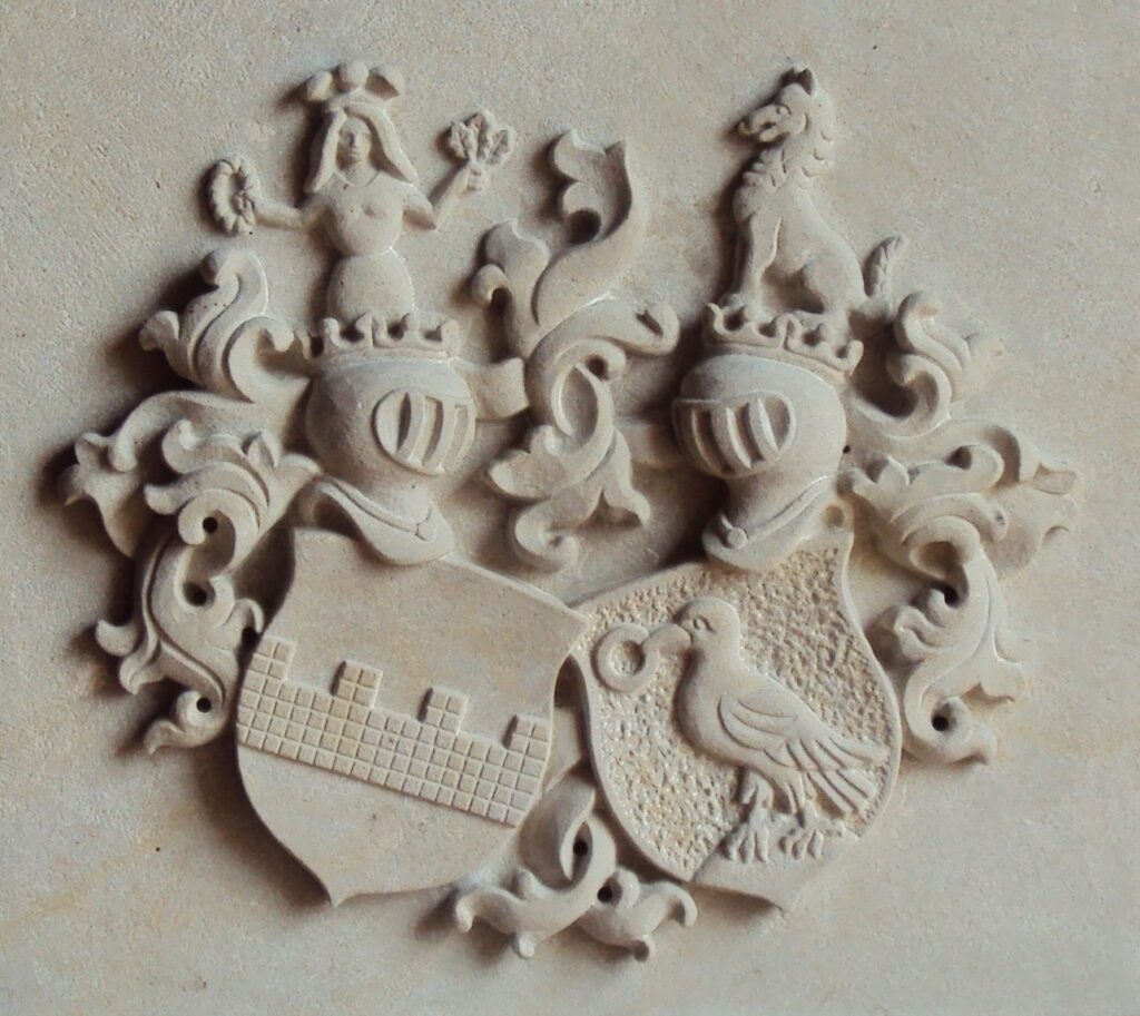 Steinrelief eines Wappens mit zwei Schilden, Helmen und Verzierungen.