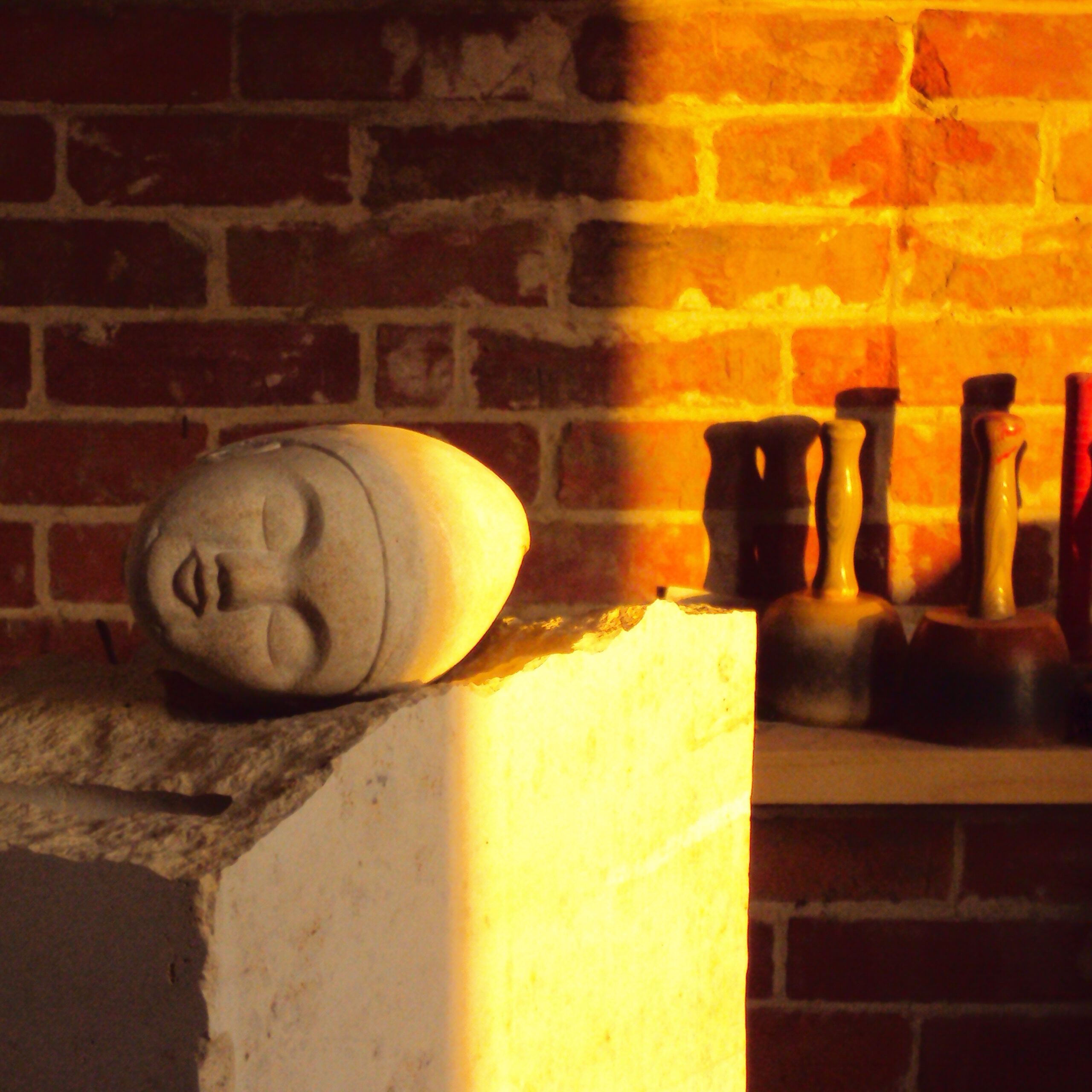 Liegender steinerner Kopf einer Skulptur im warmen Sonnenlicht.