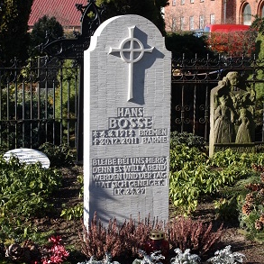 Heller Grabstein mit Kreuzrelief und Inschrift.