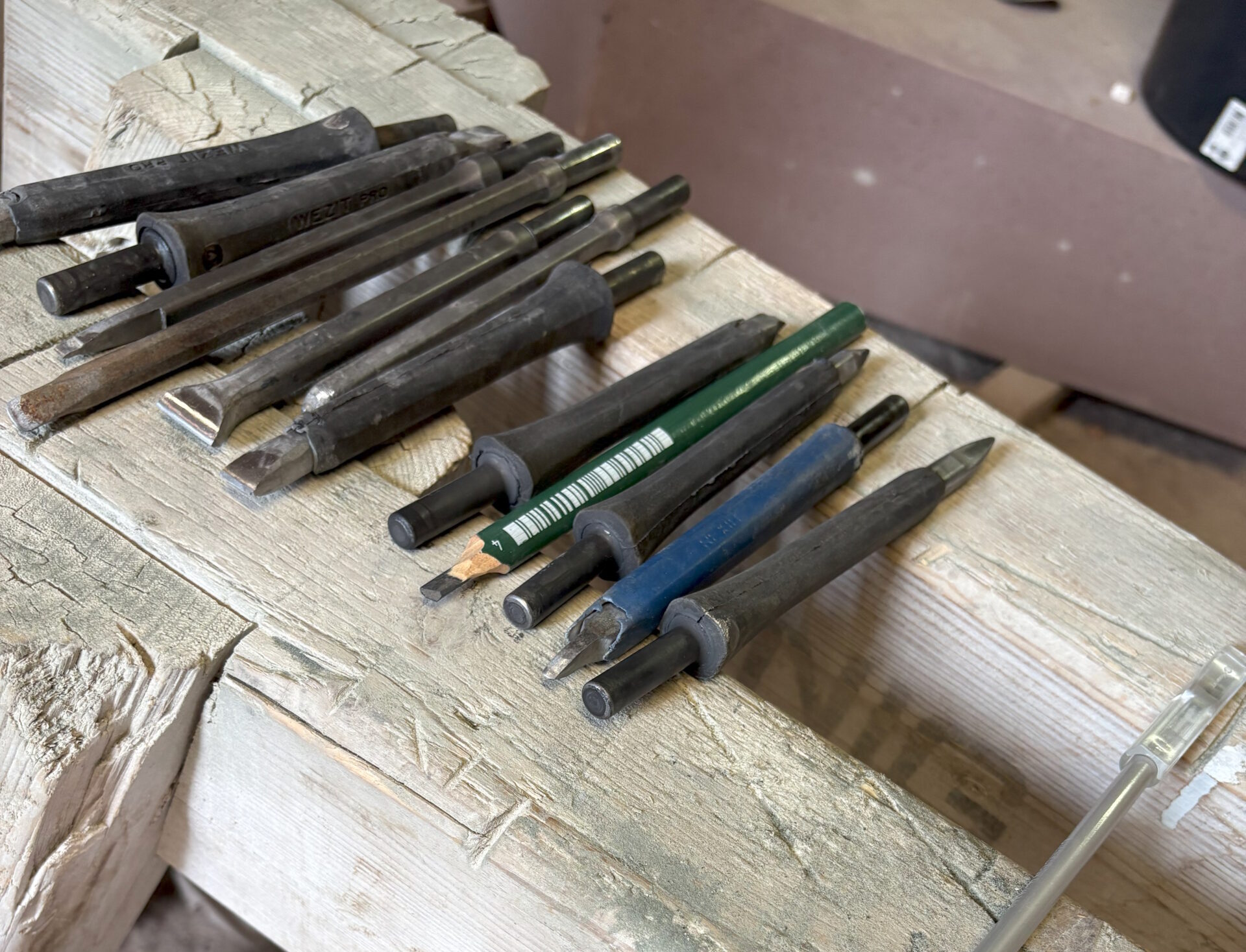 Auswahl verschiedener Steinmetzwerkzeuge auf einer Holzbank.