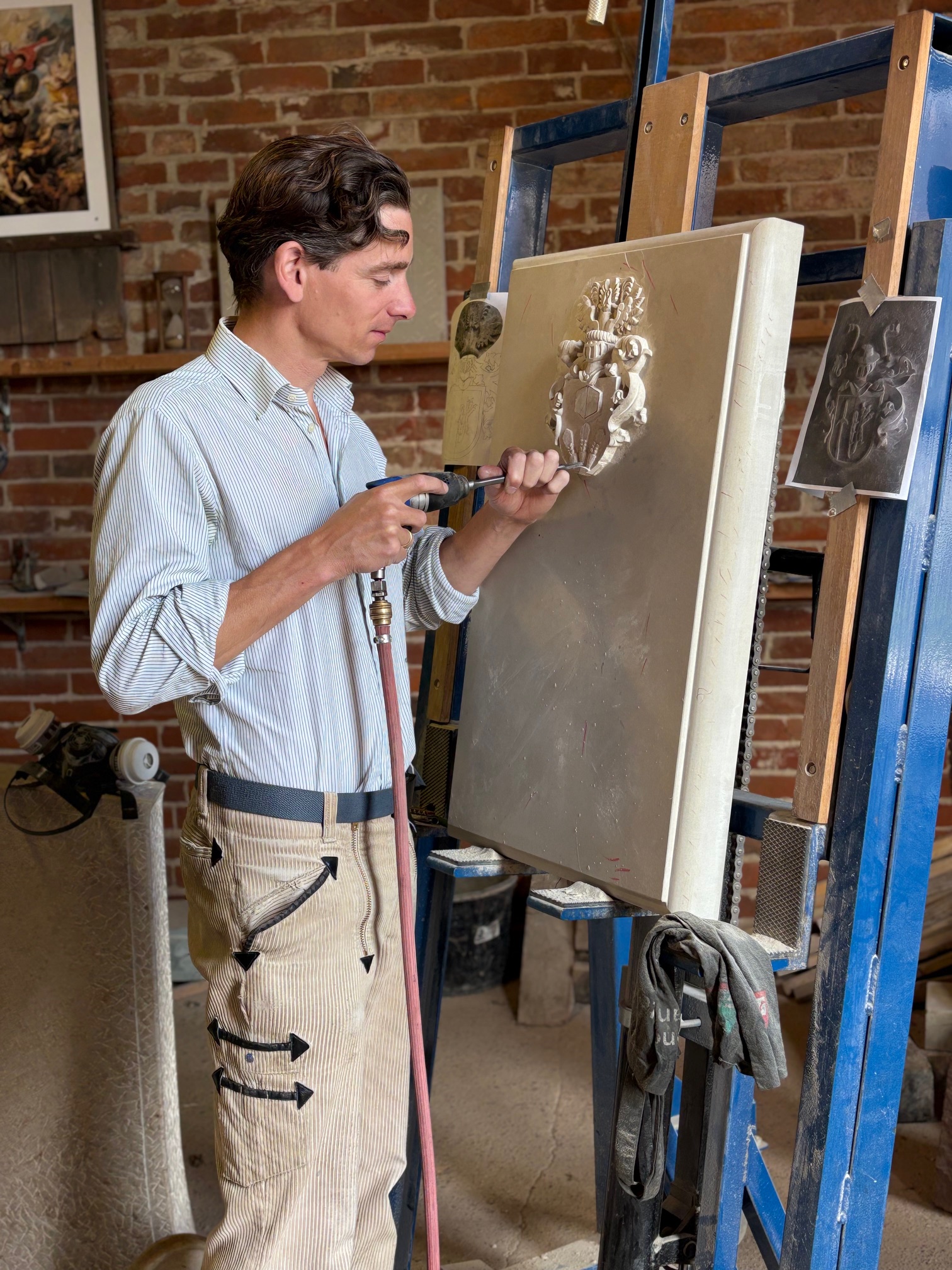 Steinmetz bei der Arbeit an einem Wappenrelief in einer Werkstatt.